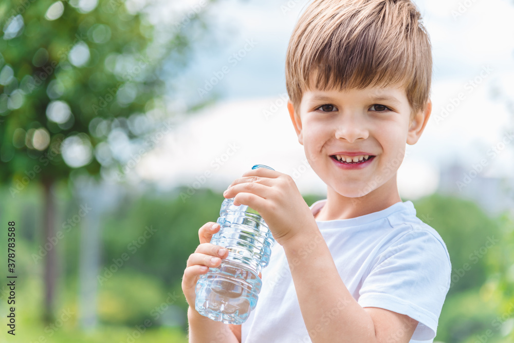 joyful child drinks clear water from a bottle on a sunny day in nature joyful child drinks clear water from a bottle on a sunny day in nature