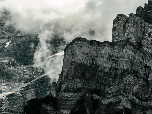 Terrible lifeless rocks, a glacier in the Alps, clouds and fog spread over the peaks of the mountains