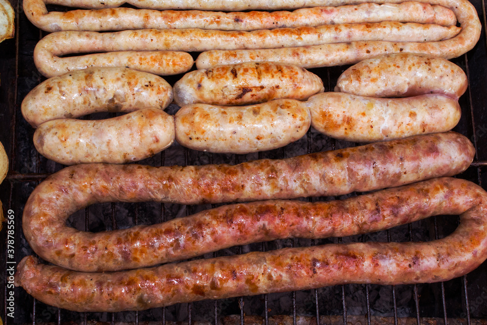 Fototapeta premium Homemade tasty fried pork sausages on a grill. metal grid grilling over hot coals for a picnic lunch