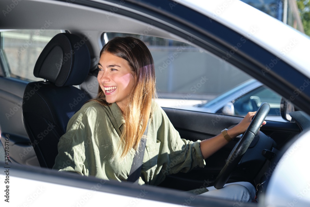 Young woman looking back in her car and laughing. Driving, holidays concepts.