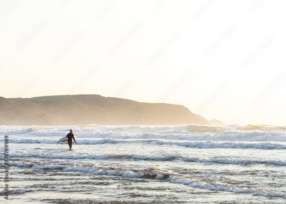 Surfer Walking out into the Ocean - Bude, Cornwall, England