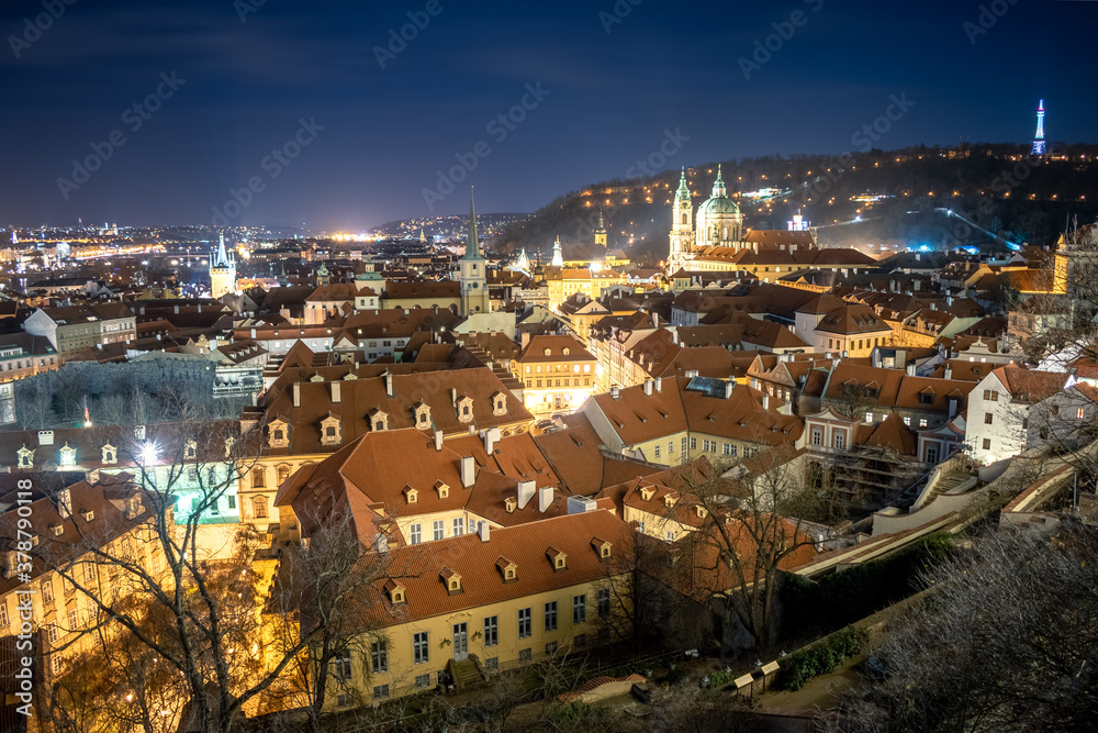 winter view from the Prague Castle to the Saint Nicholas church on Malá Strana in the historical center of Prague. Park on the Petřín hill in the background. typical red rooftops in the foreground 