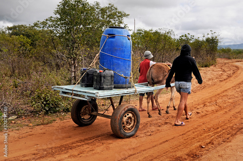 Sertanejos transportando galão de água em carroça em zona rural. photo