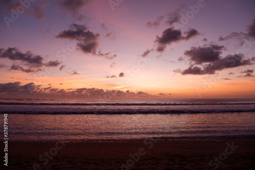 A dramatic sunset view on Kuta beach, Bali, with gradations of purple, orange and blue sky