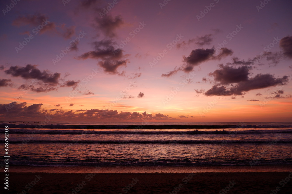 Fototapeta premium A dramatic sunset view on Kuta beach, Bali, with gradations of purple, orange and blue sky