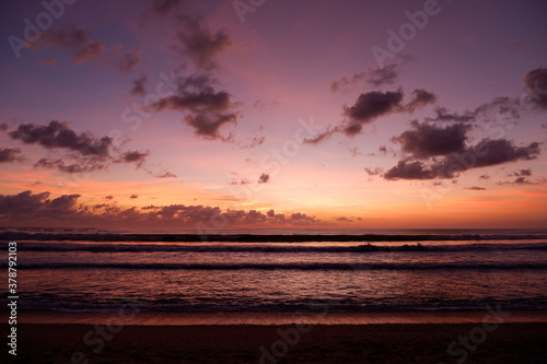 A dramatic sunset view on Kuta beach, Bali, with gradations of purple, orange and blue sky