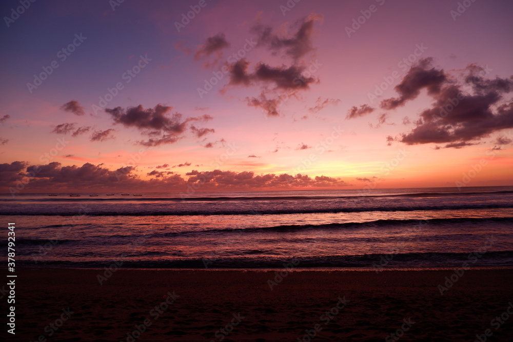 A dramatic sunset view on Kuta beach, Bali, with gradations of purple, orange and blue sky A dramatic sunset view on Kuta beach, Bali, with gradations of purple, orange and blue sky