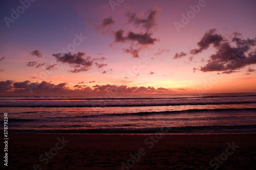 A dramatic sunset view on Kuta beach, Bali, with gradations of purple, orange and blue sky