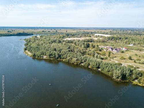 Green banks of a country river. Aerial drone view, sunny summer day.