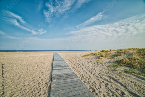 Amager Strand romantic wooden pathway or boardwalk on the beach leading to a calm Baltic Sea. Few people walk in the distance conveying relax, realisation concept. Way or path to success illustration