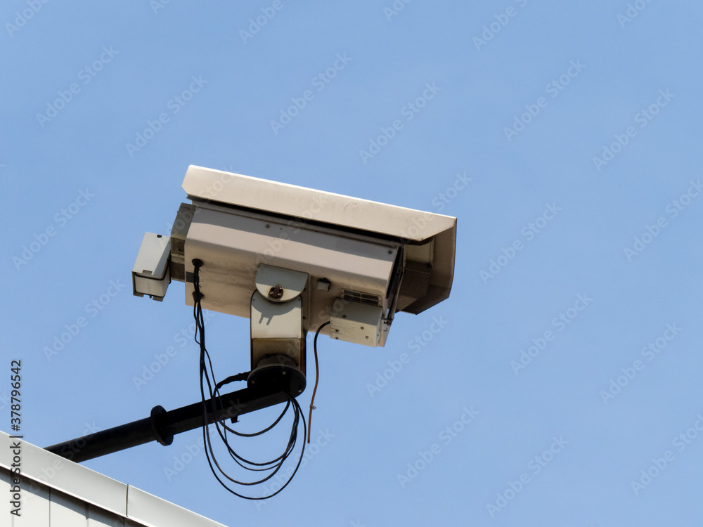 A large closed circuit televison video camera mounted on a building for sourvelinace purposes