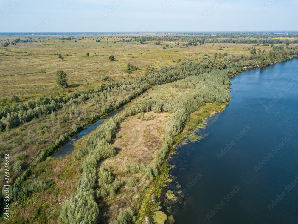 Aerial drone view. The bend of a wide river among green meadows. Sunny summer day. Aerial drone view. The bend of a wide river among green meadows. Sunny summer day.