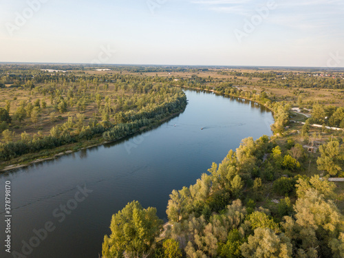 Green banks of a country river. Aerial drone view, sunny summer day.