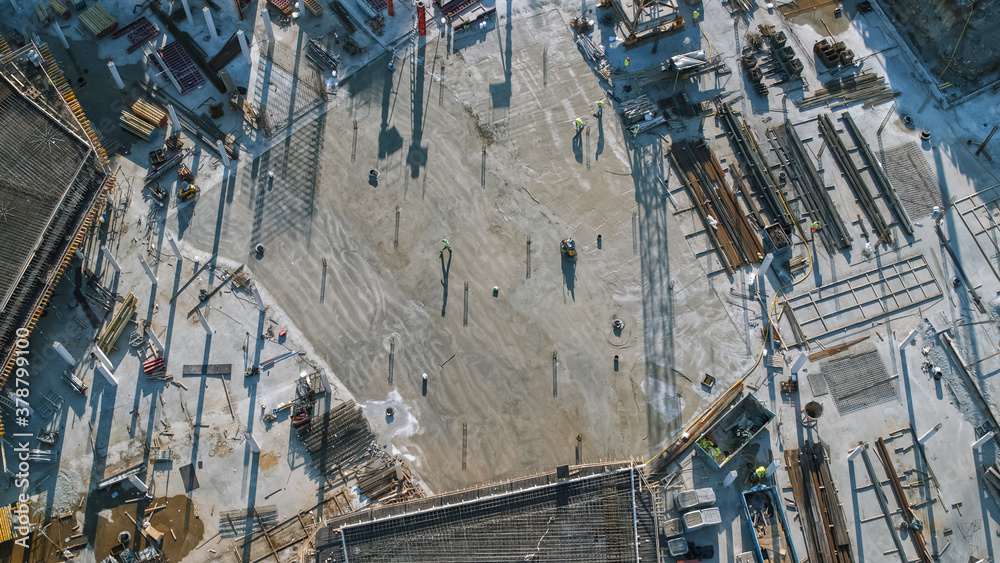 Aerial Shot of a New Constructions Development Site with High Tower Cranes Building Real Estate. Heavy Machinery and Construction Workers are Employed. Top Down View.