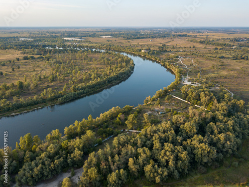 Aerial drone view. The bend of a wide river among green meadows. Sunny summer day.