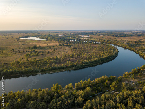 Aerial drone view. The bend of a wide river among green meadows. Sunny summer day.