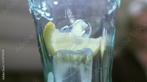 Pouring Coca-Cola into a glass with ice and lemon. Slow motion shot 50 fps to 24 fps.