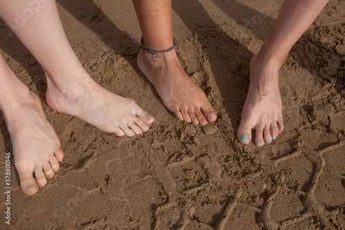 Closeup detail of four diverse female feets in the sand 