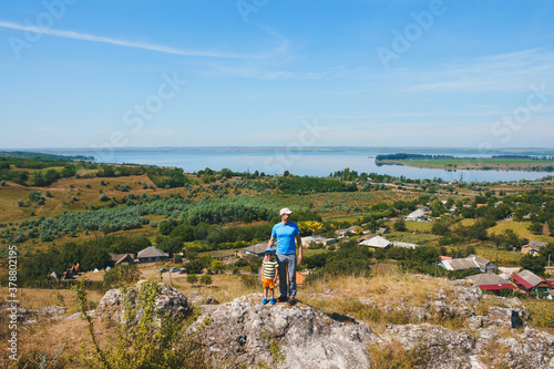 father and son on hill with river view