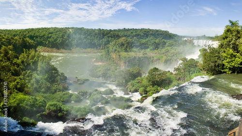 Large nature panorama of Iguacu  Iguazu  waterfall cascade on border of Brazil and Argentina. Amazing view of falls Cataratas in bright Sunny weather. Concept of travel. Copyright space for site
