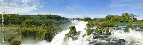 Large nature panorama of Iguacu (Iguazu) waterfall cascade on border of Brazil and Argentina. Amazing view of falls Cataratas in bright Sunny weather. Concept of travel. Copyright space for site