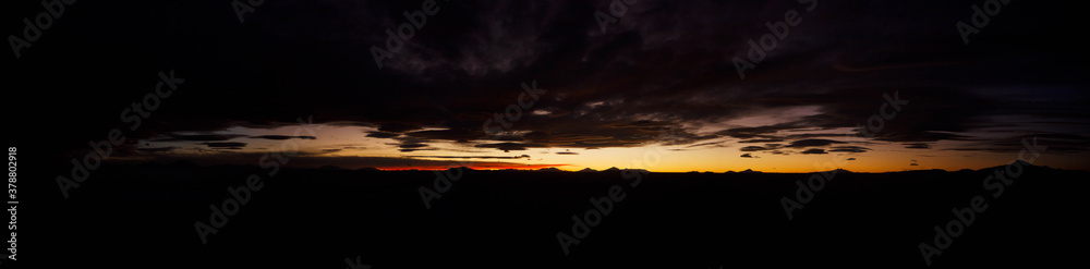 Large natural panorama of salar de Uyuni salt marsh in Bolivia at sunset. Amazing colorful view of setting sun late in evening in good weather. Concept of travel. Copyright space for the site