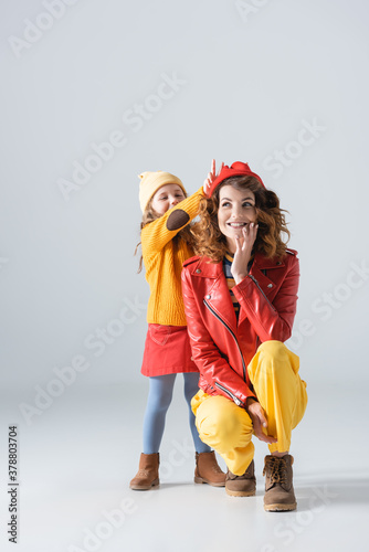 mother and daughter in colorful red and yellow outfits having fun on grey background