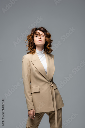 elegant woman in beige suit posing isolated on grey