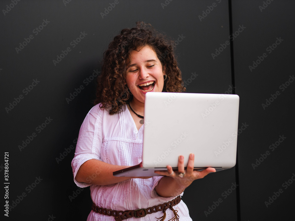 A Caucasian woman with curly hair holding a laptop A Caucasian woman with curly hair holding a laptop