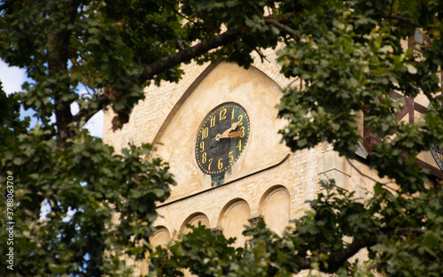 Bell tower clock of Dubulti lutheran church in latvian seaside resort city Jurmala. Floral framing view. photo