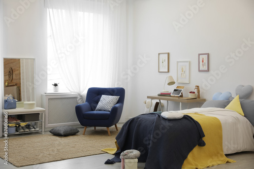 Modern teenager's room interior with bed and armchair © New Africa