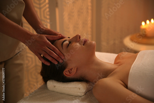 Young woman receiving head massage in spa salon