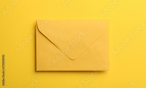 Paper envelope on yellow background, top view
