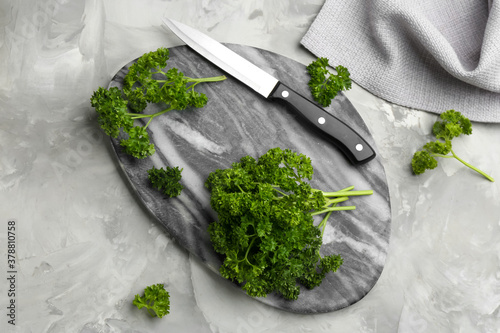 Fresh curly parsley, cutting board and knife on grey table, flat lay