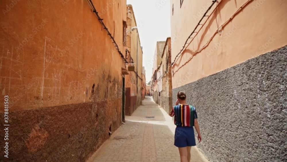 Lone female traveler walks in narrow streets of city Marrakech in Morocco, slow
