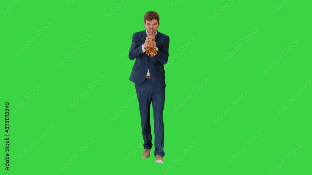 Young man in suit playing a trumpet while walking on a Green Screen, Chroma Key. Young man in suit playing a trumpet while walking on a Green Screen, Chroma Key.