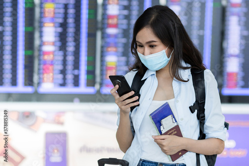 Asian woman traveler checking her flight schedule in the airport.