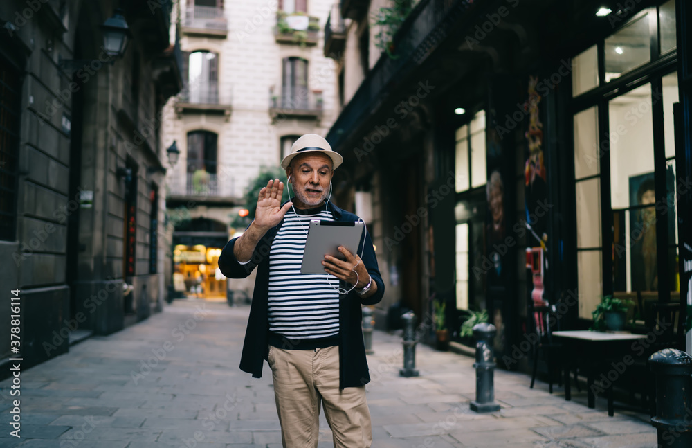 Happy senior man messaging on tablet on street in town