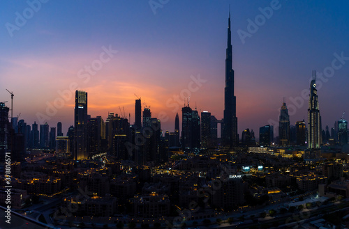 Iconic panorama at sunset of Burj Khalifa and Dubai Skyline as sun sets with blue and purple colors and other skyscrapers in the Middle East 
