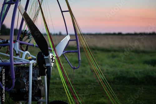 Closeup of a motorized paragliding trolley with a no-spin engine, propeller and colorful lines on the takeoff field on a beautiful evening. Extreme sports. Paragliding and small aircraft. photo