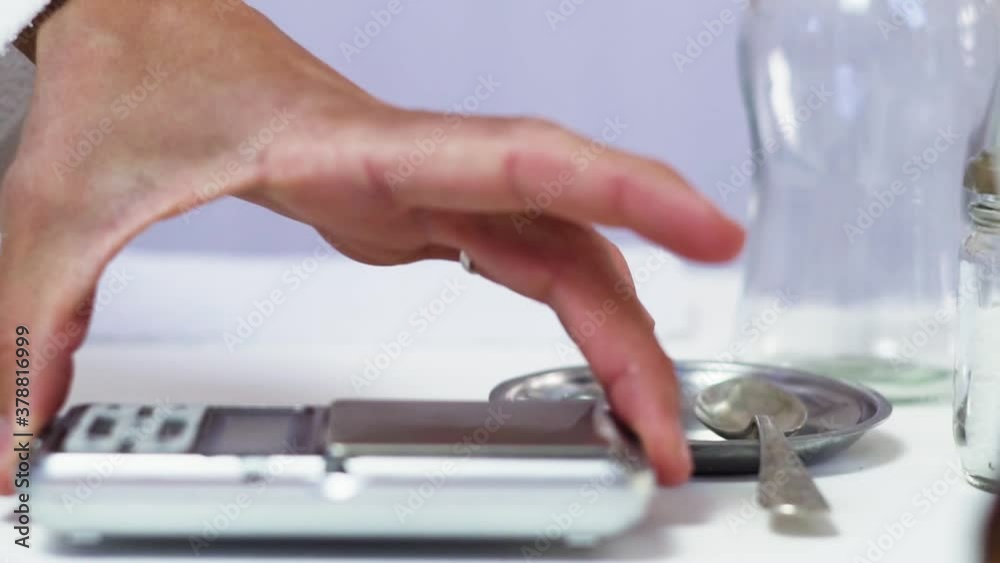 Preparing the scale and glass container for measuring drugs - Close up Preparing the scale and glass container for measuring drugs - Close up