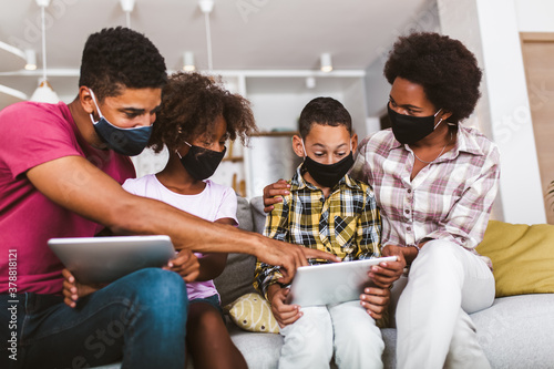 Family at home.African american family wearing protective masks using digital tablet at home.