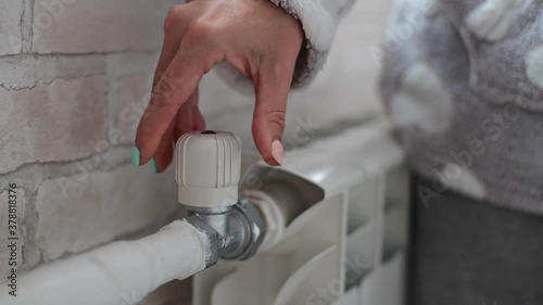 The woman opens the valve of the radiator heating.