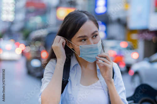 Asian traveler women wearing surgical mask while in the city with blur background.