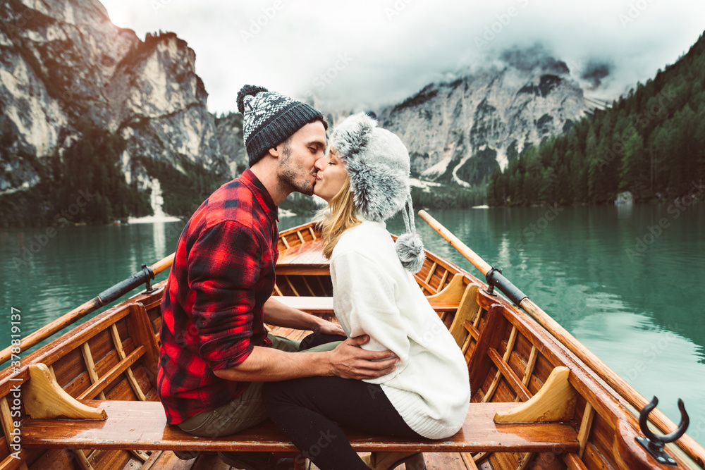 Romantic kiss of a couple of adults visiting an alpine lake at Braies Italy. Tourist in love spending loving moments together at autumn mountains. Couple, wanderlust and travel concept. Romantic kiss of a couple of adults visiting an alpine lake at Braies Italy. Tourist in love spending loving moments together at autumn mountains. Couple, wanderlust and travel concept.