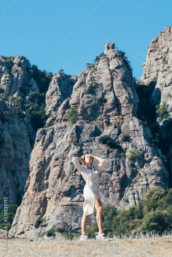 Young woman in safari dress on the rocks in the mountains Young woman in safari dress on the rocks in the mountains