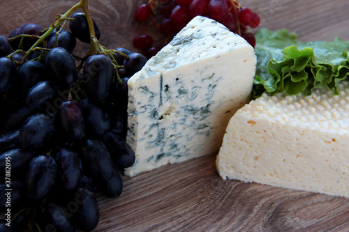 A piece of blue cheese and grapes. Gourmet products.