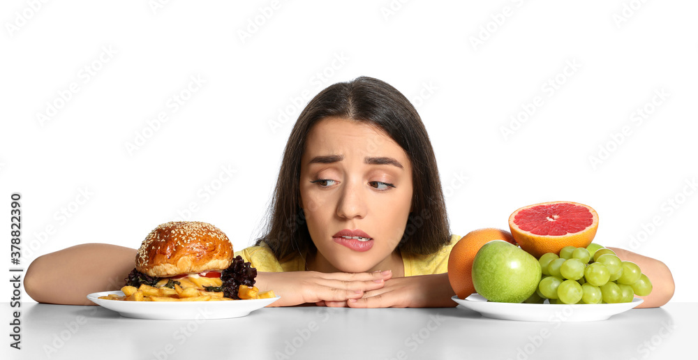 Doubtful woman choosing between fruits and burger with French fries on white background Doubtful woman choosing between fruits and burger with French fries on white background