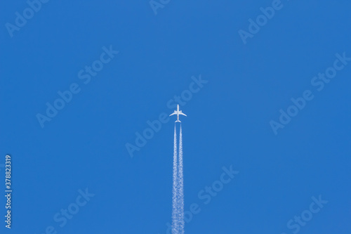 Jet plane flying in the blue sky. Wake leaving trace or steam jet, viewed from below in nadir shot