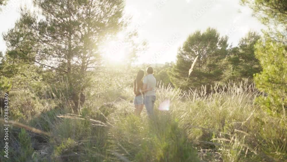 Romantic Couple Enjoying Their Time Together While Admiring The Beautiful Sunset Setting From The Fields. - wide shot Romantic Couple Enjoying Their Time Together While Admiring The Beautiful Sunset Setting From The Fields. - wide shot